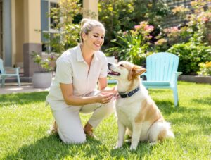 Owner praises and pets their dog after giving a pill, reinforcing positivity in a bright backyard setting.